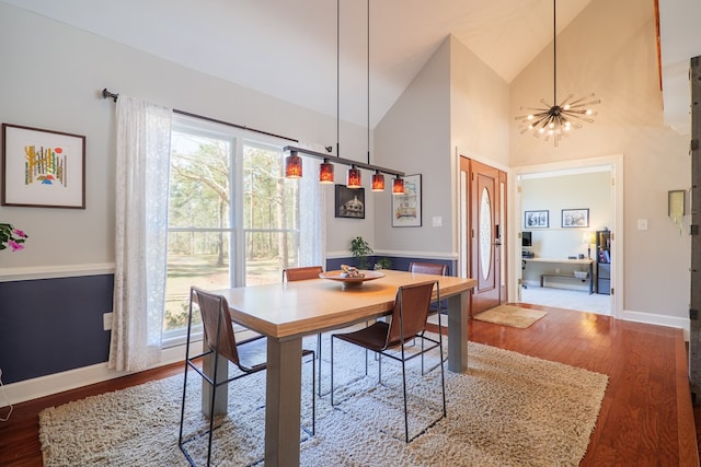 dining area with baseboards, high vaulted ceiling, wood finished floors, and a notable chandelier