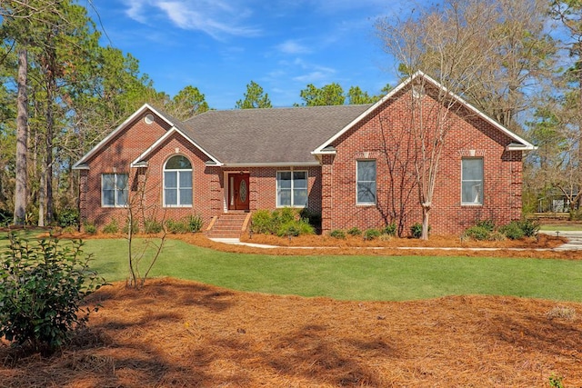 single story home with roof with shingles, a front yard, and brick siding