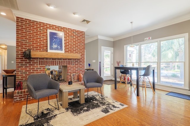 living area with a brick fireplace, visible vents, crown molding, and wood finished floors