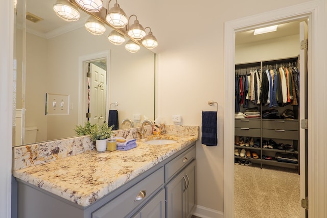 bathroom featuring ornamental molding, a walk in closet, visible vents, and vanity