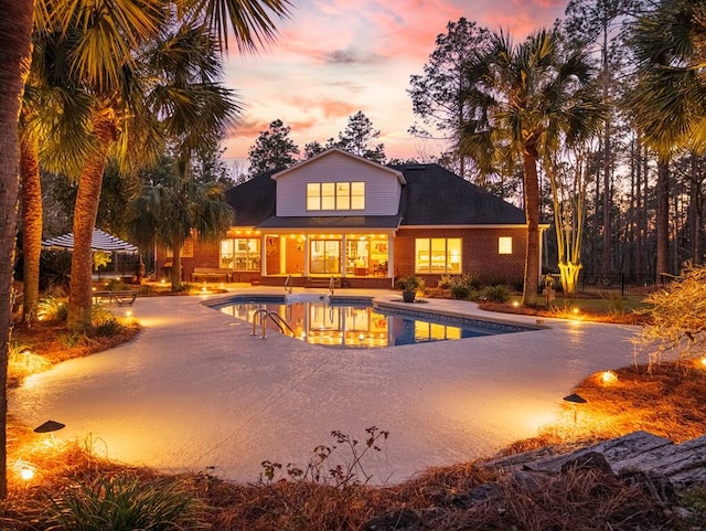 exterior space with a patio area, an outdoor pool, and brick siding