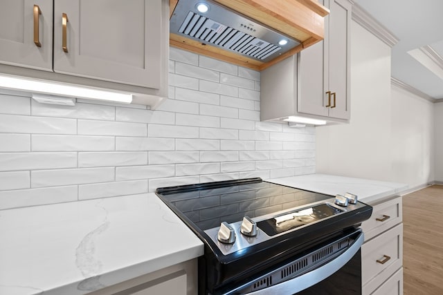 2204 N Oak St, Valdosta, GA 31602 - kitchen featuring range with electric cooktop, wall chimney exhaust hood, backsplash, light stone countertops, and light wood finished floors