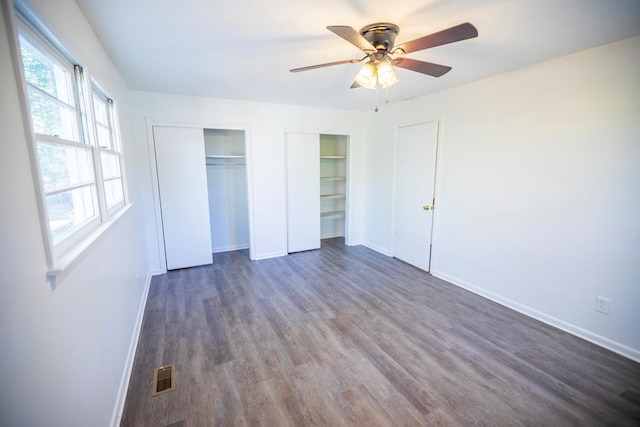 2205 Park Ln, Valdosta, GA 31602 - unfurnished bedroom featuring baseboards, visible vents, a ceiling fan, dark wood finished floors, and multiple closets