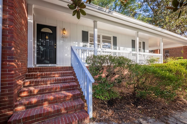 property entrance with a porch and brick siding