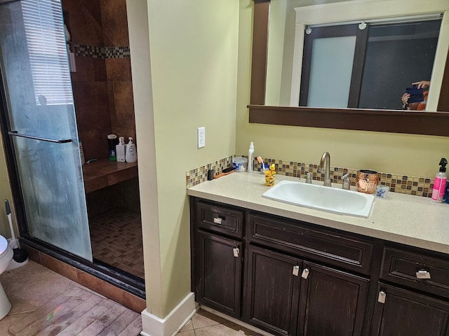 bathroom with decorative backsplash, a stall shower, vanity, baseboards, and toilet