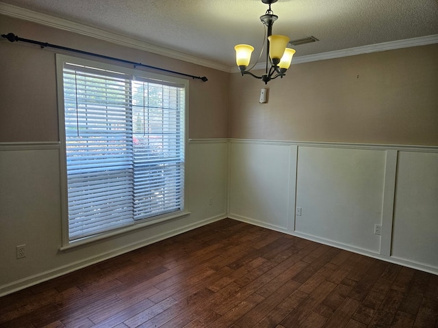 empty room with a textured ceiling, visible vents, wood finished floors, a wainscoted wall, and a notable chandelier