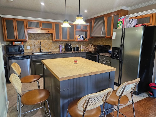 kitchen featuring a sink, appliances with stainless steel finishes, wall chimney range hood, and tasteful backsplash