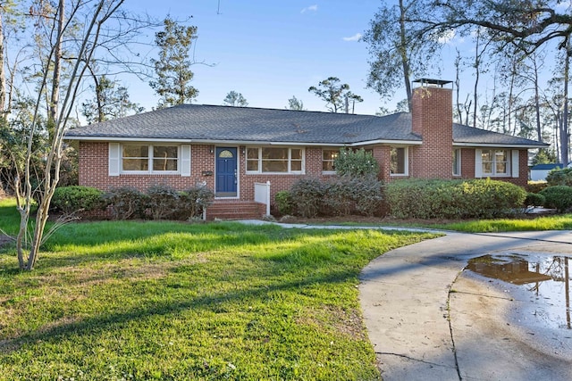 single story home featuring brick siding, a chimney, concrete driveway, and a front yard