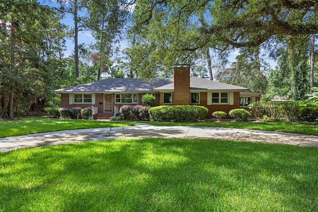 ranch-style home with brick siding, a chimney, and a front yard