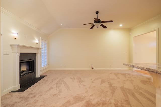 unfurnished living room featuring a tile fireplace, carpet floors, baseboards, vaulted ceiling, and crown molding