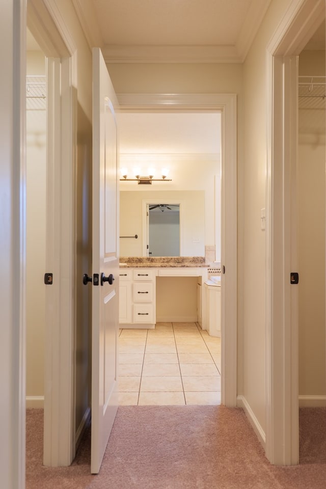 hallway with light carpet, light tile patterned flooring, and crown molding