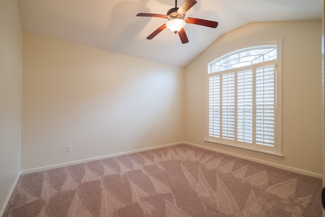 spare room featuring a ceiling fan, carpet, vaulted ceiling, and baseboards