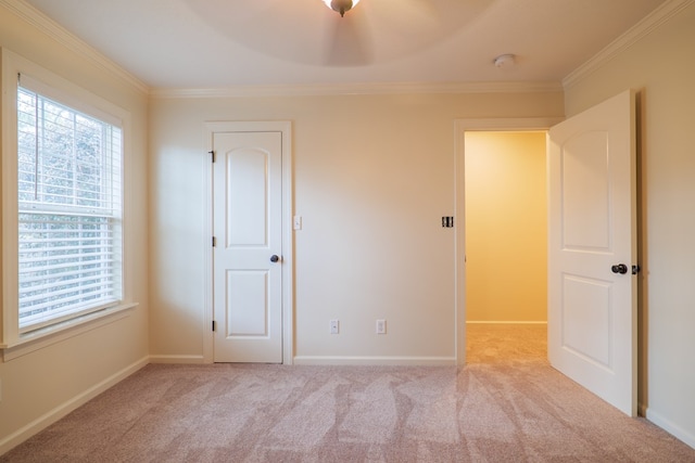 spare room with light carpet, baseboards, and crown molding