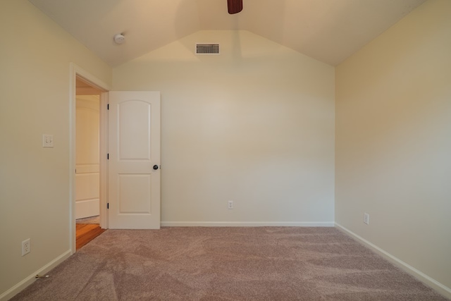 carpeted empty room featuring vaulted ceiling, visible vents, and baseboards