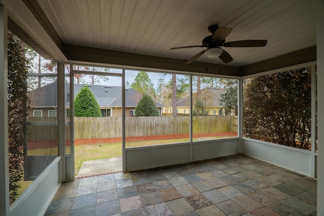 unfurnished sunroom featuring wood ceiling, a residential view, and a ceiling fan