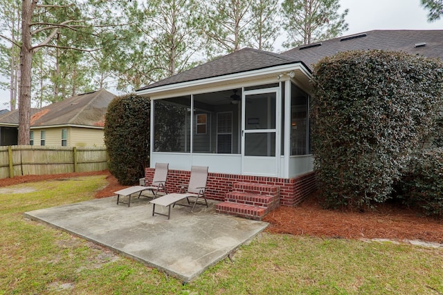 rear view of property with a shingled roof, fence, a sunroom, a yard, and a patio area