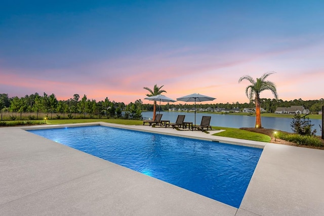 pool at dusk with a patio and a water view