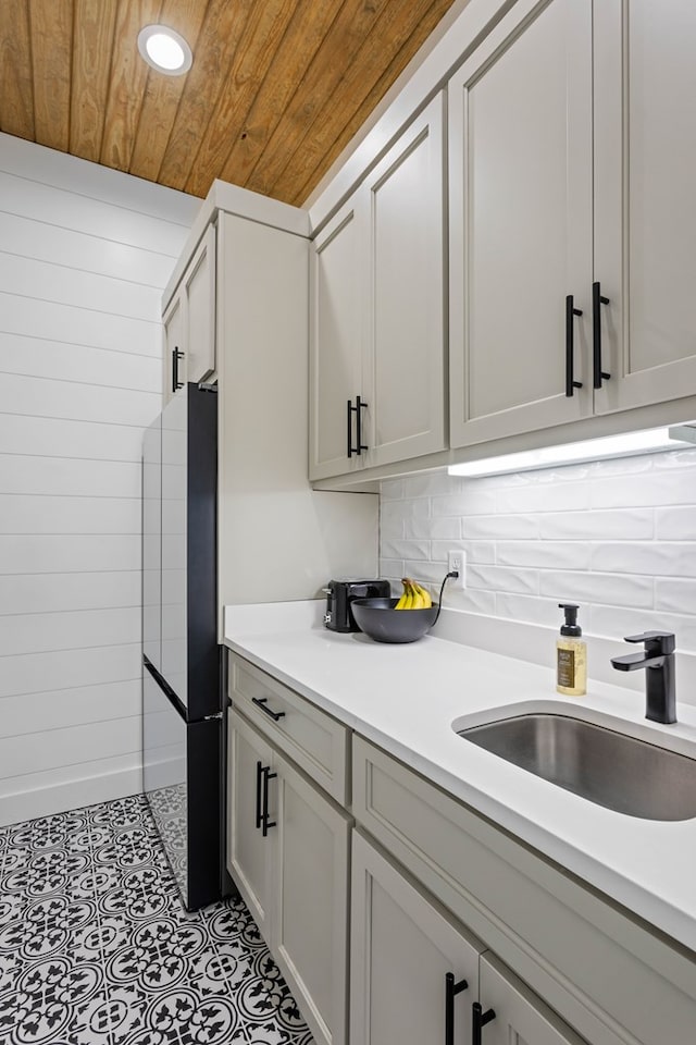 kitchen with sink, wooden ceiling, backsplash, refrigerator, and white cabinets