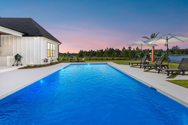 pool at dusk with a patio area