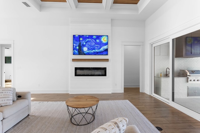 living room with beamed ceiling, a fireplace, wood-type flooring, and ornamental molding