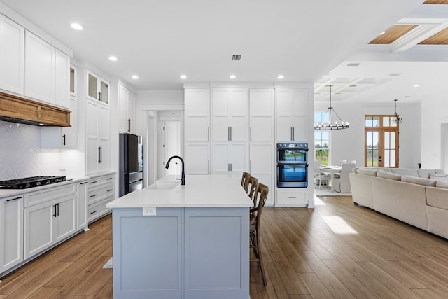 kitchen featuring a center island with sink, white cabinets, stainless steel appliances, and light hardwood / wood-style floors