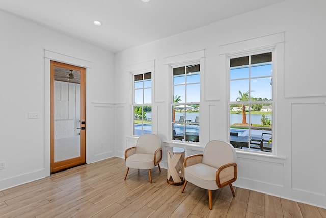 living area featuring a water view and light hardwood / wood-style flooring