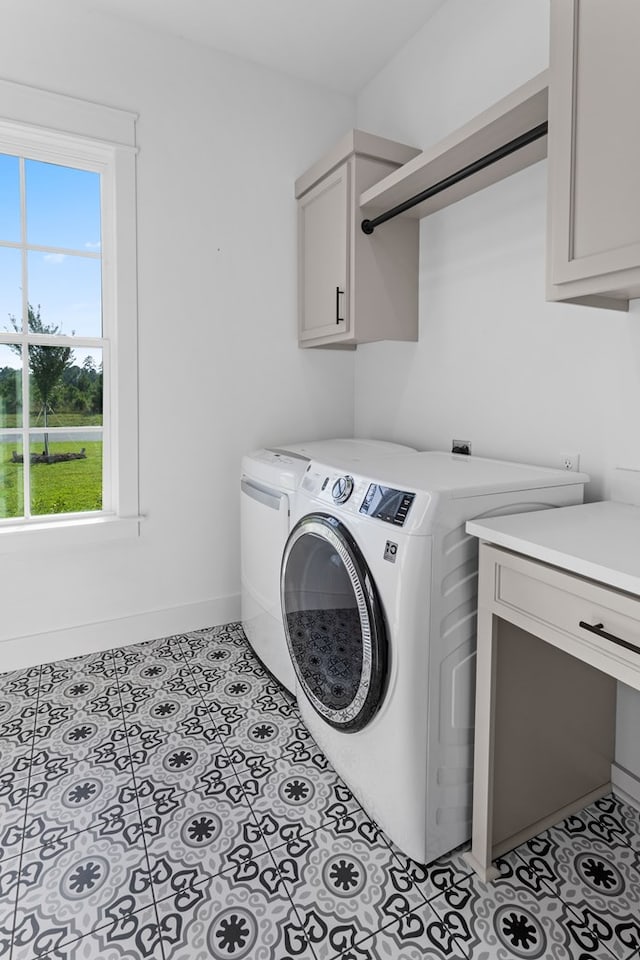 clothes washing area featuring cabinets, light tile patterned floors, and washing machine and dryer