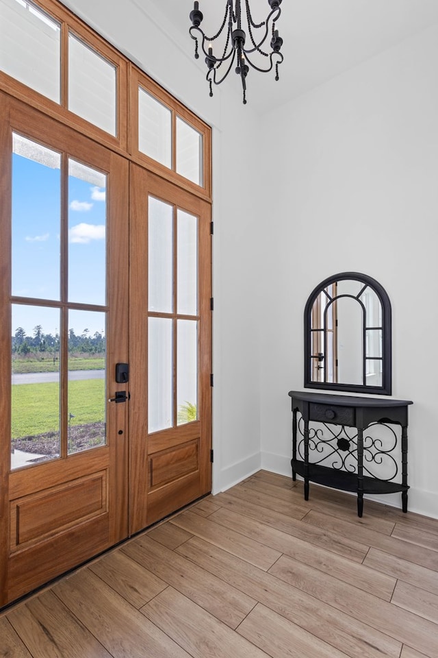 entryway featuring a healthy amount of sunlight, an inviting chandelier, french doors, and light hardwood / wood-style flooring