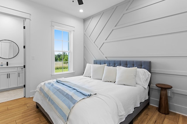 bedroom with hardwood / wood-style floors, ensuite bath, ceiling fan, and sink