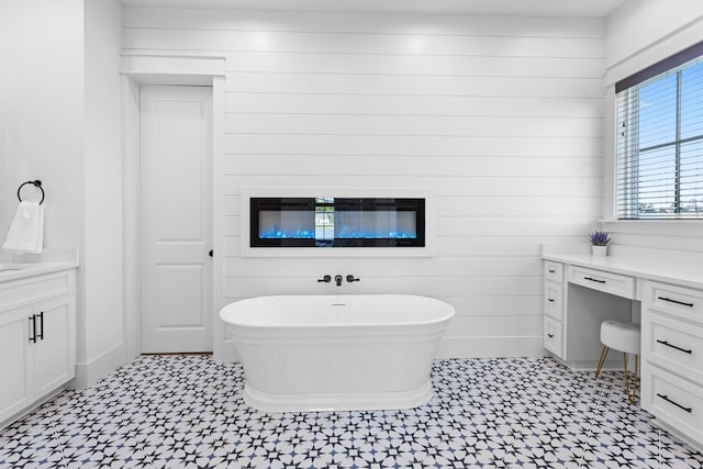 bathroom featuring a bathing tub, vanity, and wood walls