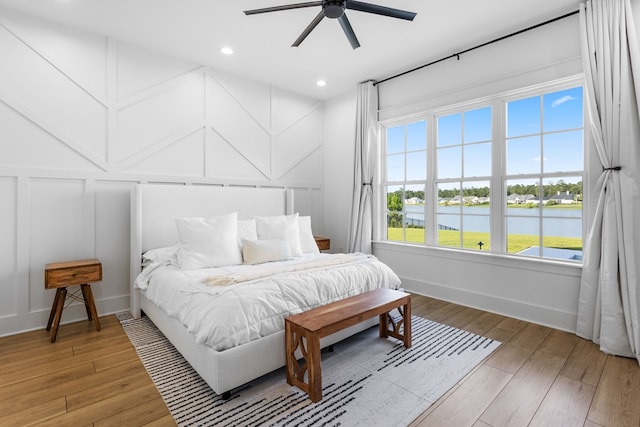 bedroom with a water view, ceiling fan, and hardwood / wood-style flooring