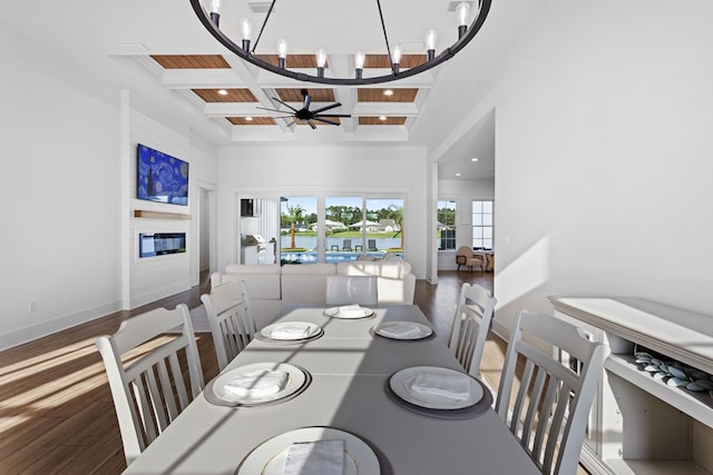 dining space with wood-type flooring, ceiling fan with notable chandelier, coffered ceiling, and beam ceiling