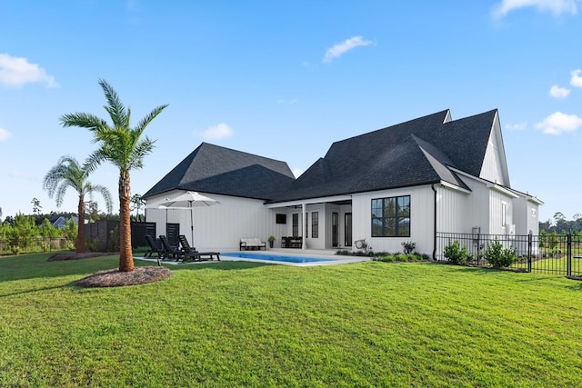 rear view of house with a lawn, a patio, and a fenced in pool