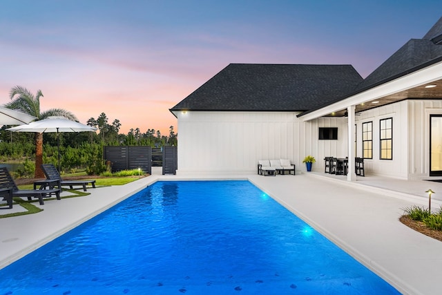 pool at dusk featuring a patio