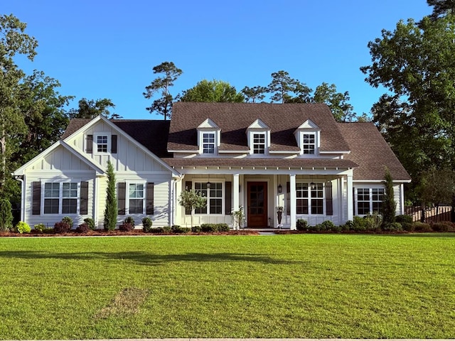 cape cod home with board and batten siding, a shingled roof, covered porch, and a front yard