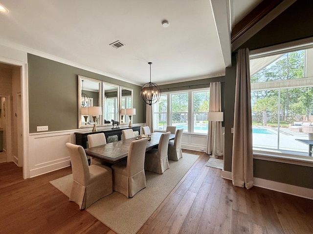 dining area with crown molding, a chandelier, visible vents, and hardwood / wood-style flooring