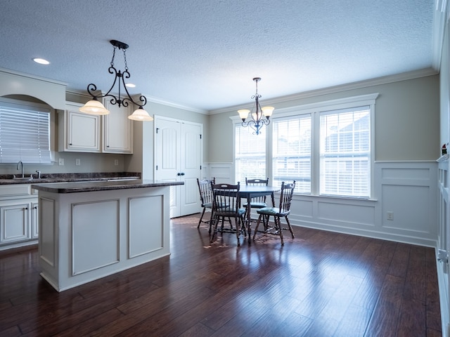 kitchen with dark wood-type flooring, sink, decorative light fixtures, a center island, and white cabinets