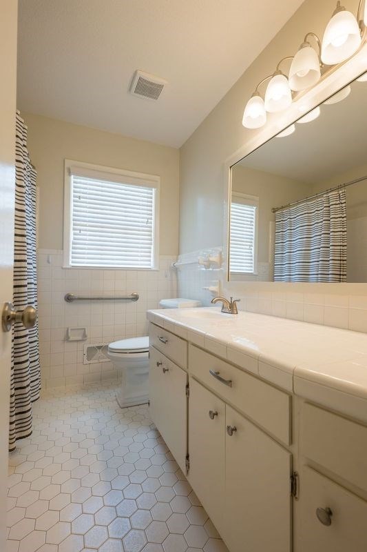 bathroom featuring toilet, tile patterned flooring, tile walls, and vanity