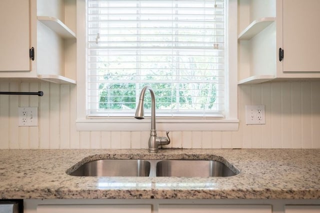 kitchen with light stone counters, sink, and white cabinets