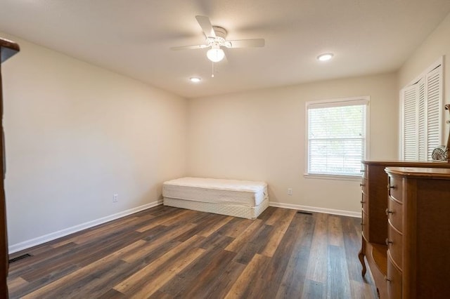 unfurnished bedroom featuring ceiling fan, a closet, and dark wood-type flooring