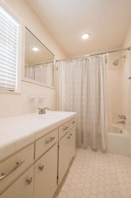 bathroom featuring a healthy amount of sunlight, shower / tub combo, tile patterned floors, and vanity