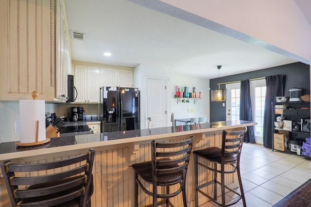 5187 Branch Point Dr, Valdosta, GA 31605 - kitchen with black fridge with ice dispenser, stove, a peninsula, a kitchen bar, and white cabinets