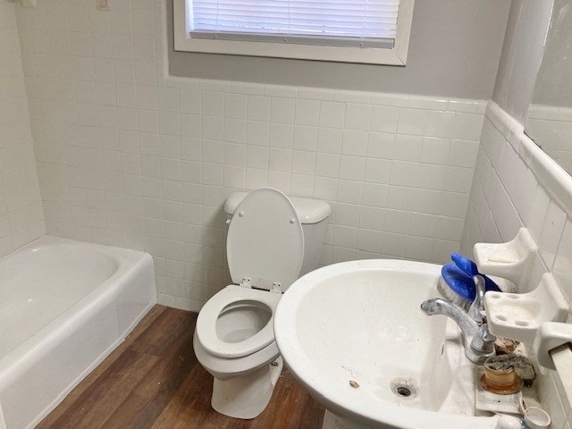 619 Lakeview Dr, Adel, GA 31620 - full bath featuring wood finished floors, a bath, tile walls, toilet, and wainscoting