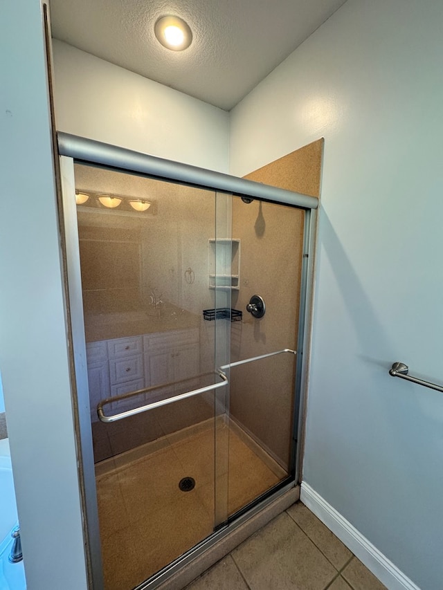 bathroom with an enclosed shower, tile patterned flooring, and a textured ceiling