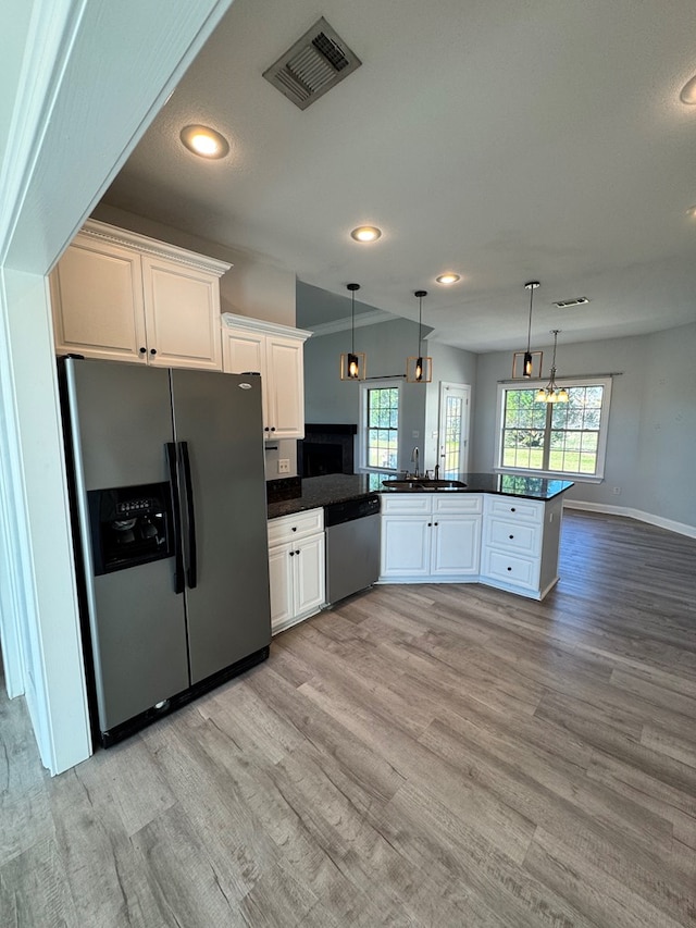 kitchen featuring stainless steel appliances, white cabinets, hanging light fixtures, and kitchen peninsula