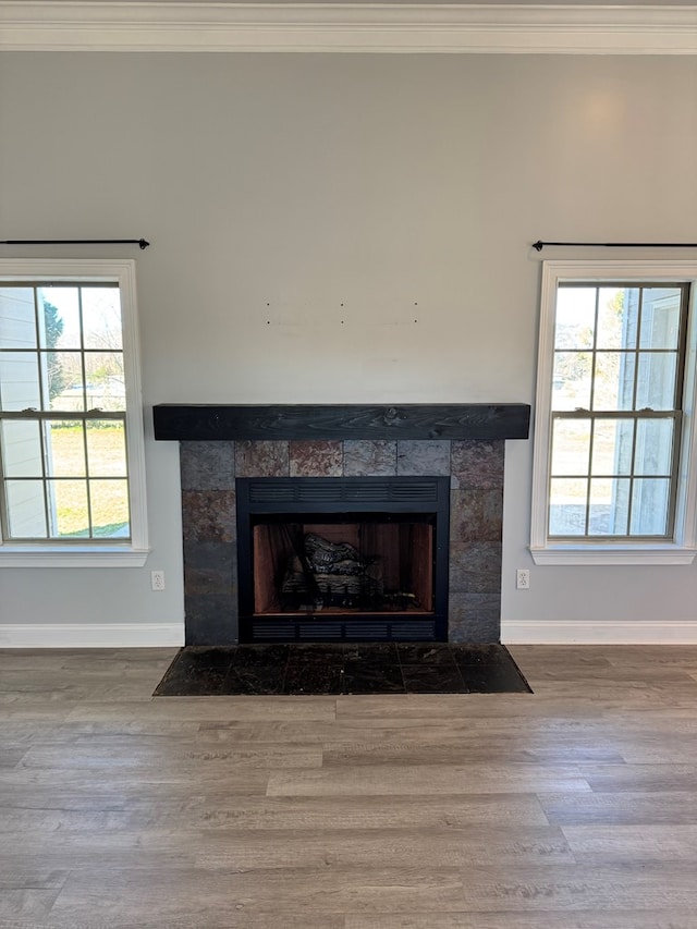 room details with a tiled fireplace, crown molding, and wood-type flooring