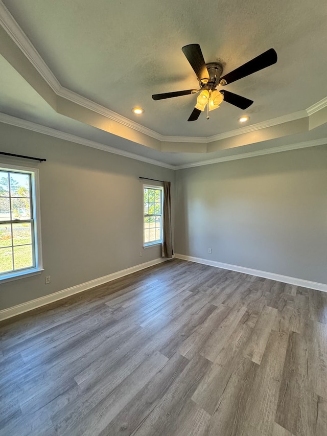 empty room featuring ornamental molding, ceiling fan, light hardwood / wood-style floors, and a raised ceiling