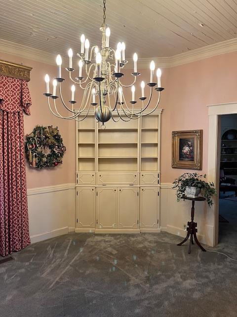 dining room with dark colored carpet, crown molding, wood ceiling, and a notable chandelier