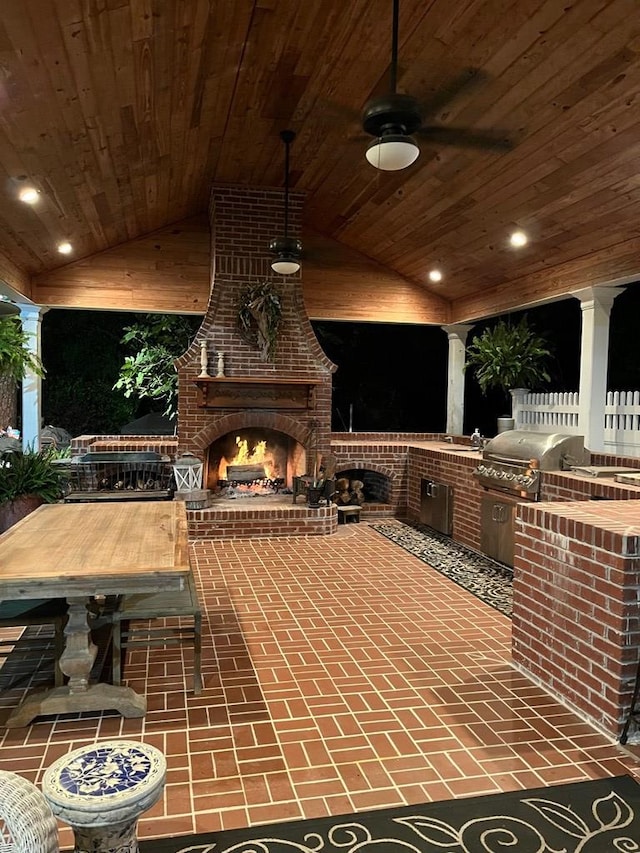 view of patio with grilling area, an outdoor kitchen, an outdoor brick fireplace, and a ceiling fan