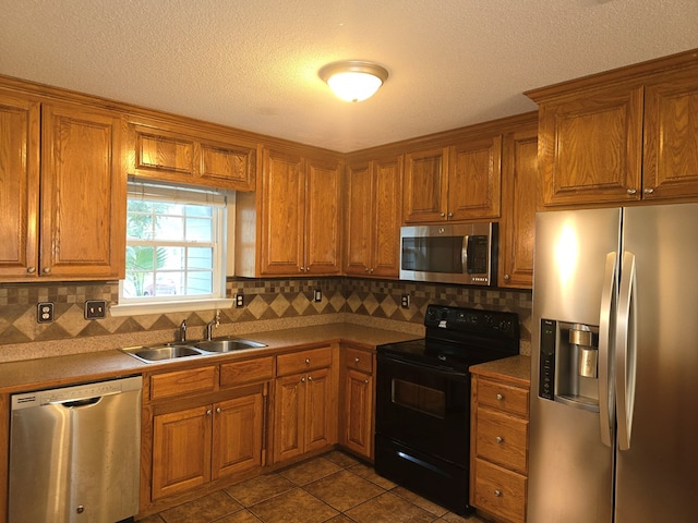 kitchen with sink, tile patterned flooring, a textured ceiling, decorative backsplash, and appliances with stainless steel finishes